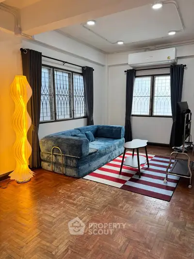 Spacious living room with stylish decor and natural light, featuring a cozy sofa and modern lighting.