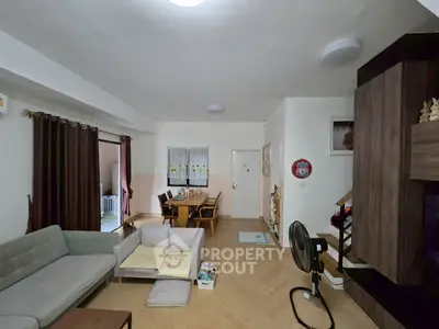 Spacious living room with modern decor and dining area, featuring cozy seating and stylish wooden flooring.