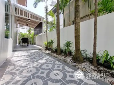 Charming outdoor patio with modern tile flooring and lush greenery