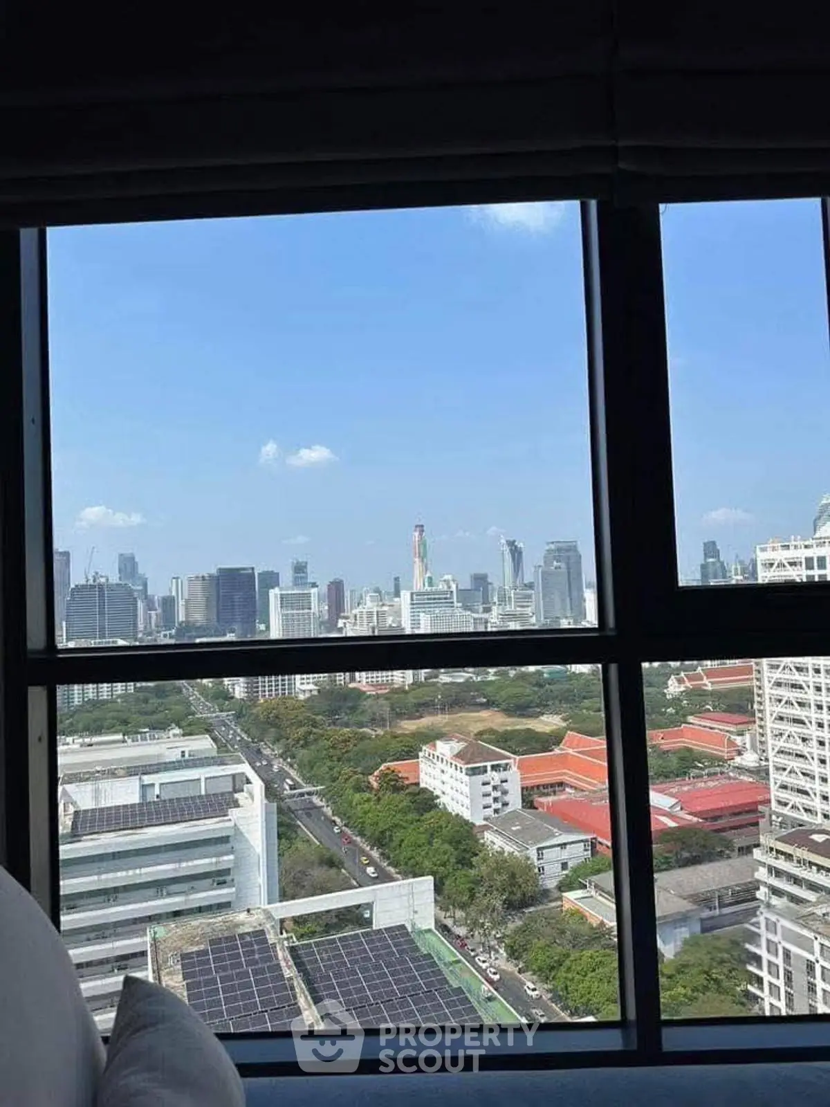 Stunning cityscape view from high-rise apartment window, showcasing urban skyline and greenery.