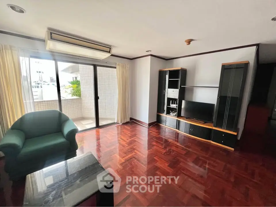 Spacious living room with polished wooden floors and balcony access in modern apartment.