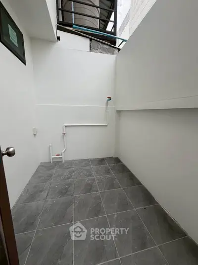 Spacious tiled outdoor area with plumbing, ideal for laundry or utility use.