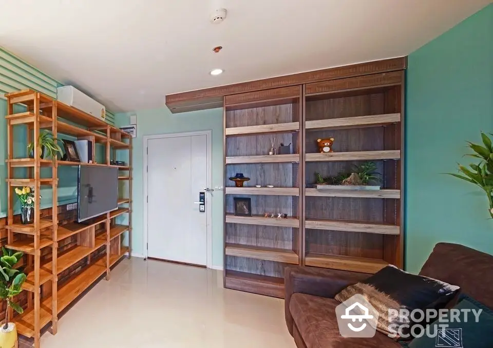 Cozy living room with teal accent wall, wooden bookshelf, and comfortable brown sofa, complemented by natural light and greenery.