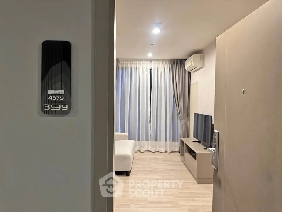 Modern apartment entrance leading to a cozy living room with sleek furniture and ambient lighting.