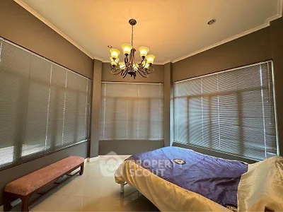 Spacious bedroom with elegant chandelier and large windows for natural light.