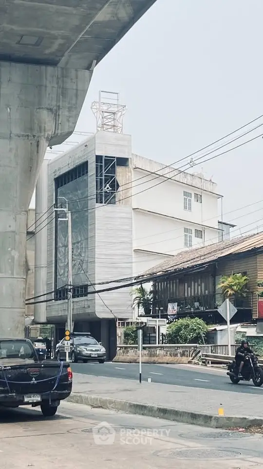 Urban street view with modern building and overpass, showcasing city living environment.