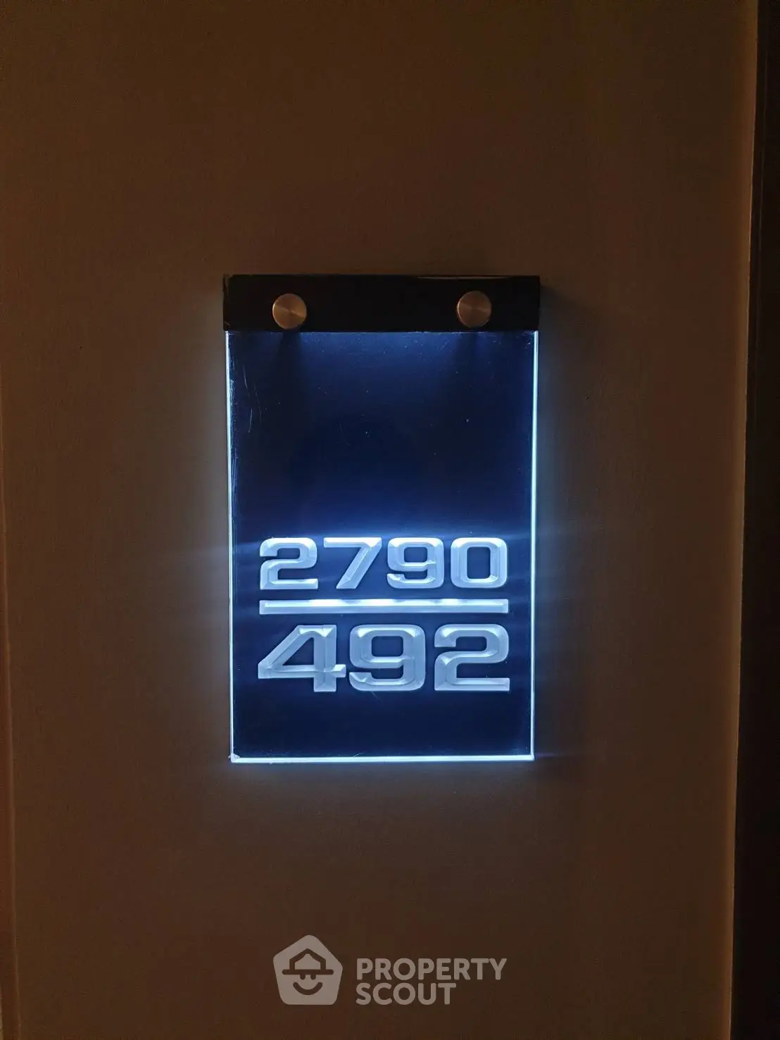 Illuminated modern apartment number sign on wall, showcasing sleek design and clear visibility.