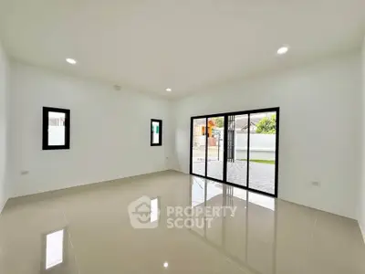Spacious modern living room with large windows and glossy tiled floor, perfect for natural light.
