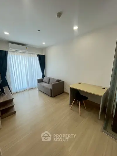 Modern living room with sofa, desk, and large window with curtains in a bright apartment.