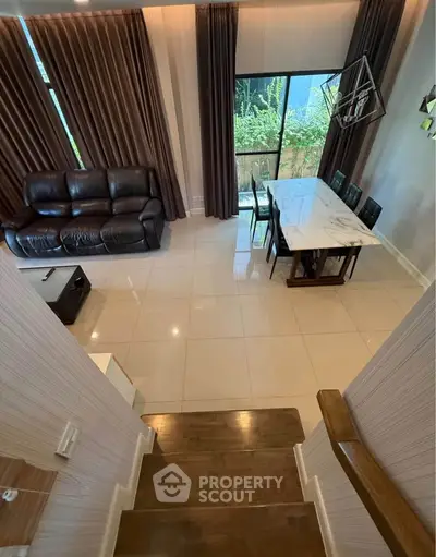 Spacious living room with elegant dining area and garden view, featuring modern decor and natural light.