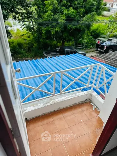 Charming small balcony with tiled floor and blue roof view, perfect for relaxing outdoors.