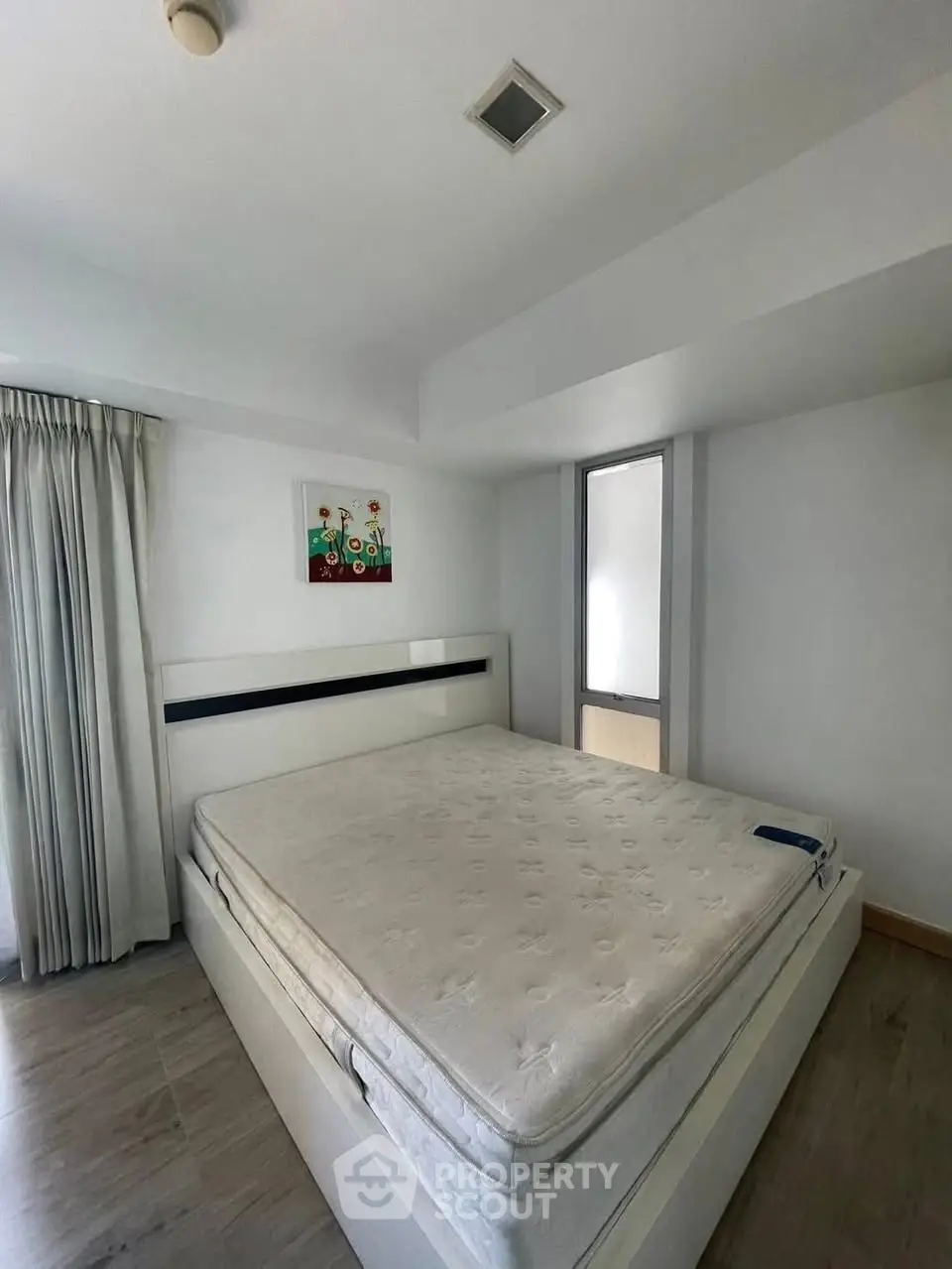 Spacious bedroom with modern decor and large window for natural light.