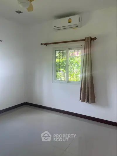 Bright empty room with air conditioning and window view of greenery.