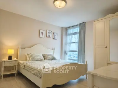 Charming bedroom with elegant white furniture and large window offering natural light.
