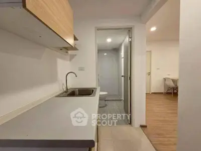 Modern compact kitchen with sleek design and adjacent bathroom in a cozy apartment.