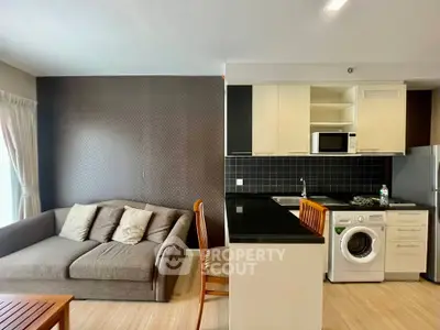Modern open-layout kitchen and living room with washing machine and cozy sofa.