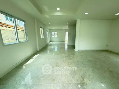 Spacious open-plan living area with large windows and glossy tiled floors