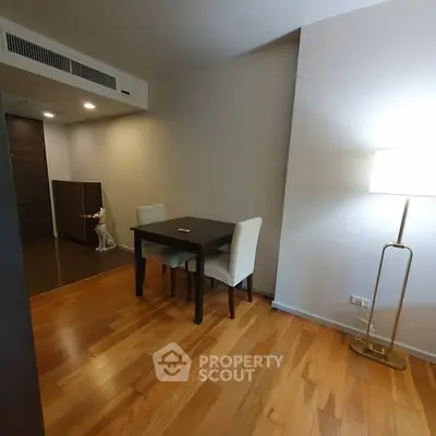 Cozy dining area with wooden flooring and modern lighting in a stylish apartment.