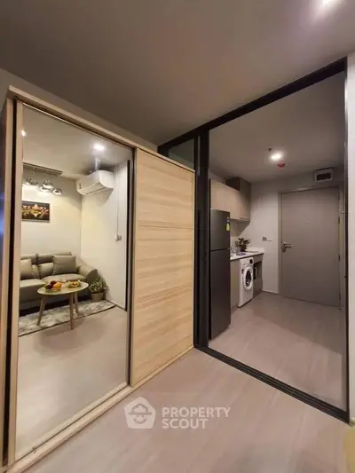 Modern apartment interior with cozy living room and kitchen featuring washing machine and fridge.