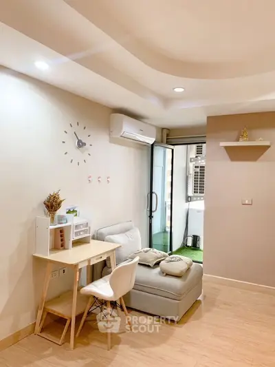 Modern living room with cozy seating and small workspace, featuring air conditioning and balcony access.