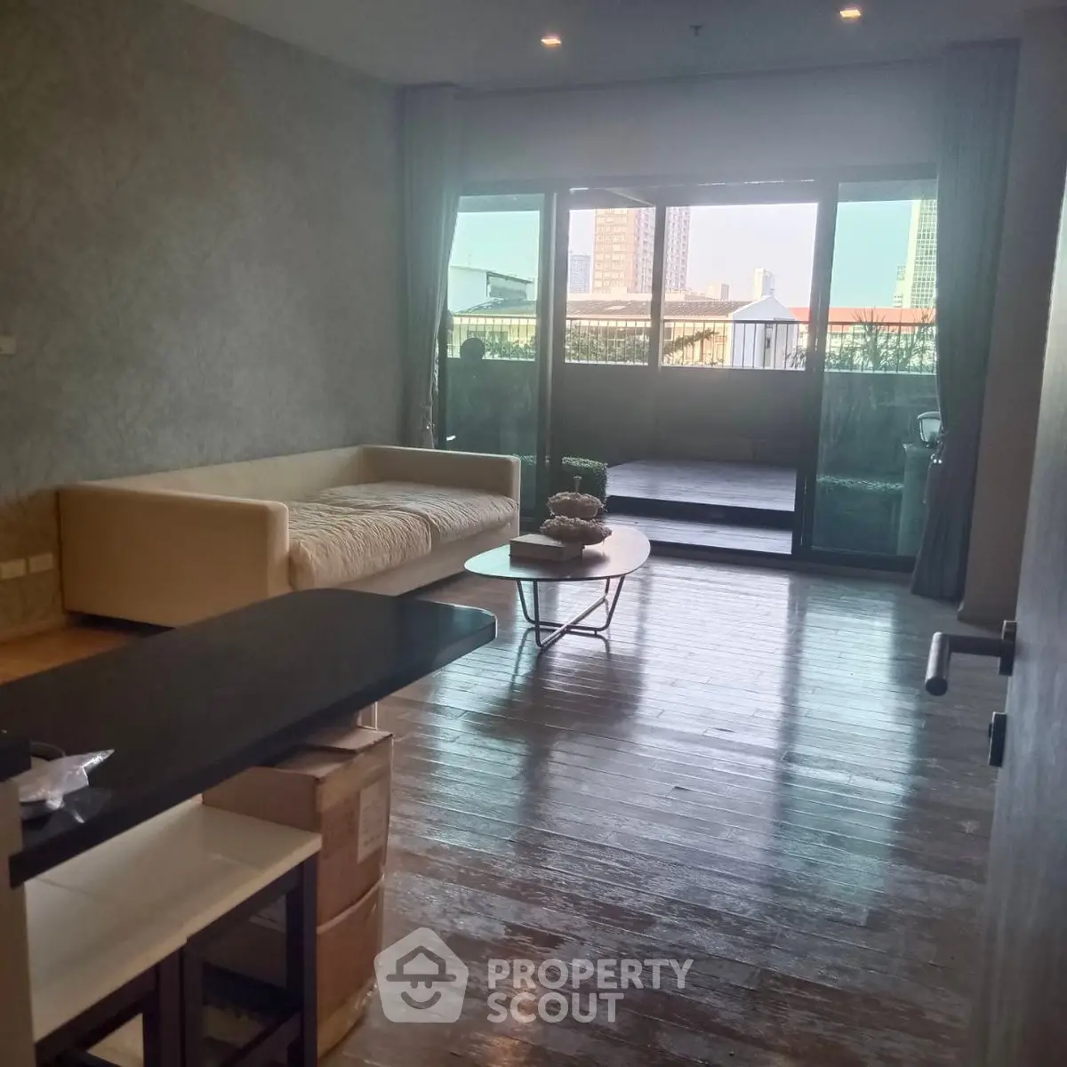 Spacious living room with large balcony and city view, featuring modern furniture and elegant decor.