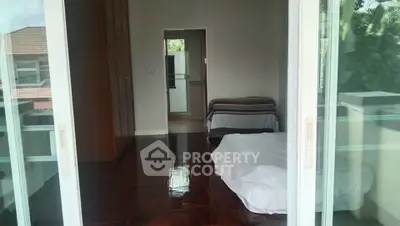 Spacious bedroom with polished wooden floors and sliding glass doors opening to a balcony.