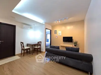 Modern living room with cozy seating and dining area, featuring stylish lighting and wooden flooring.