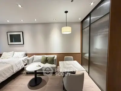 Modern studio apartment with cozy bed, stylish sofa, and elegant dining area.