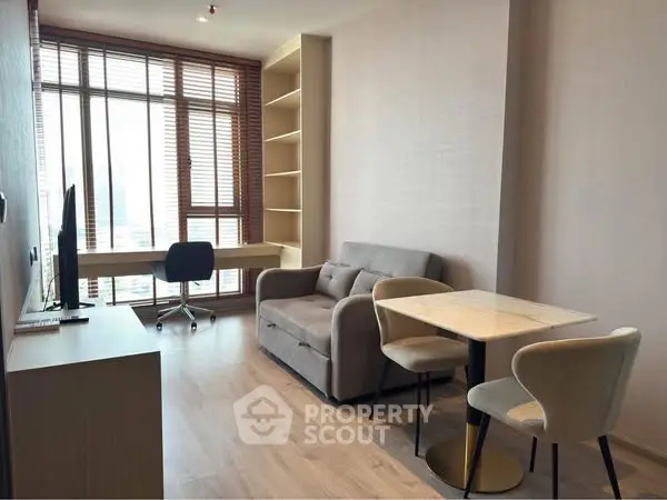 Modern living room with natural light, cozy seating, and workspace in a stylish apartment.