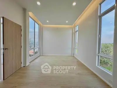 Spacious empty room with large windows and wooden flooring, perfect for customization.