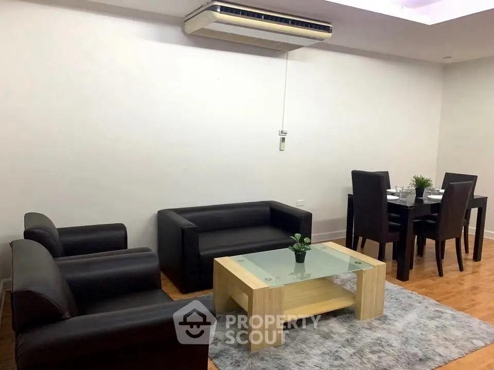 Modern living room with sleek black furniture and dining area