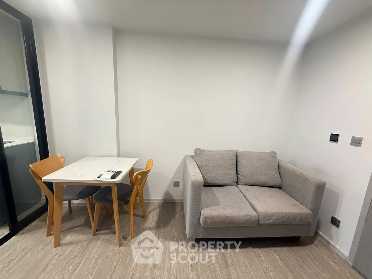 Modern living room with cozy gray sofa and dining table in a minimalist apartment.
