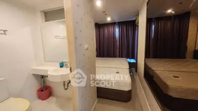 Compact bedroom with ensuite bathroom, featuring large mirror and cozy ambiance.