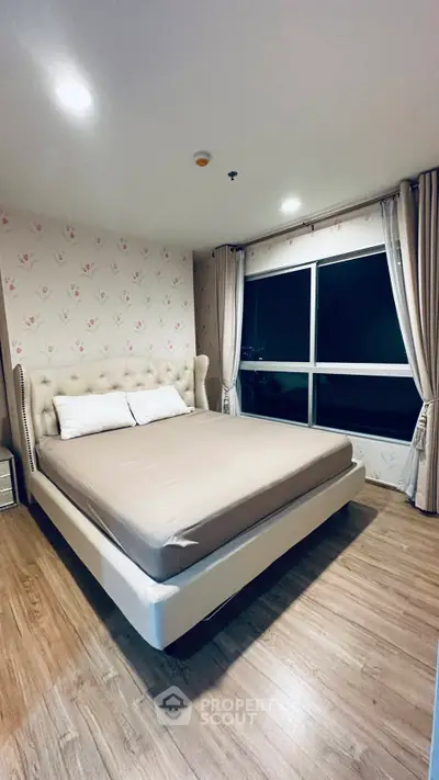 Spacious bedroom with elegant decor and large window offering city views.