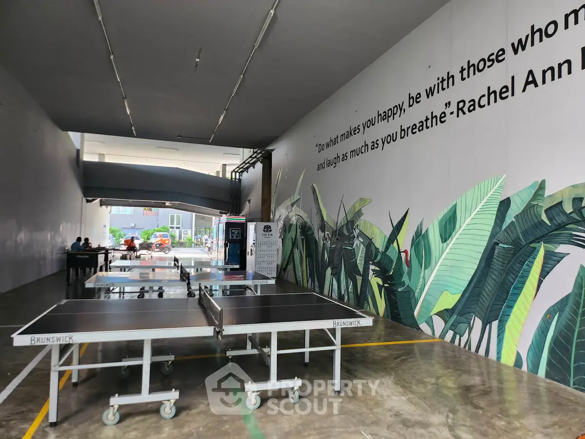 Modern recreational area with ping pong tables and vibrant wall art in a residential complex.