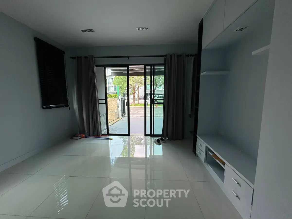 Spacious modern living room with large sliding glass doors leading to outdoor area, featuring sleek built-in storage.