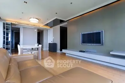 Modern living room with sleek TV setup and elegant dining area, featuring stylish lighting and contemporary design.