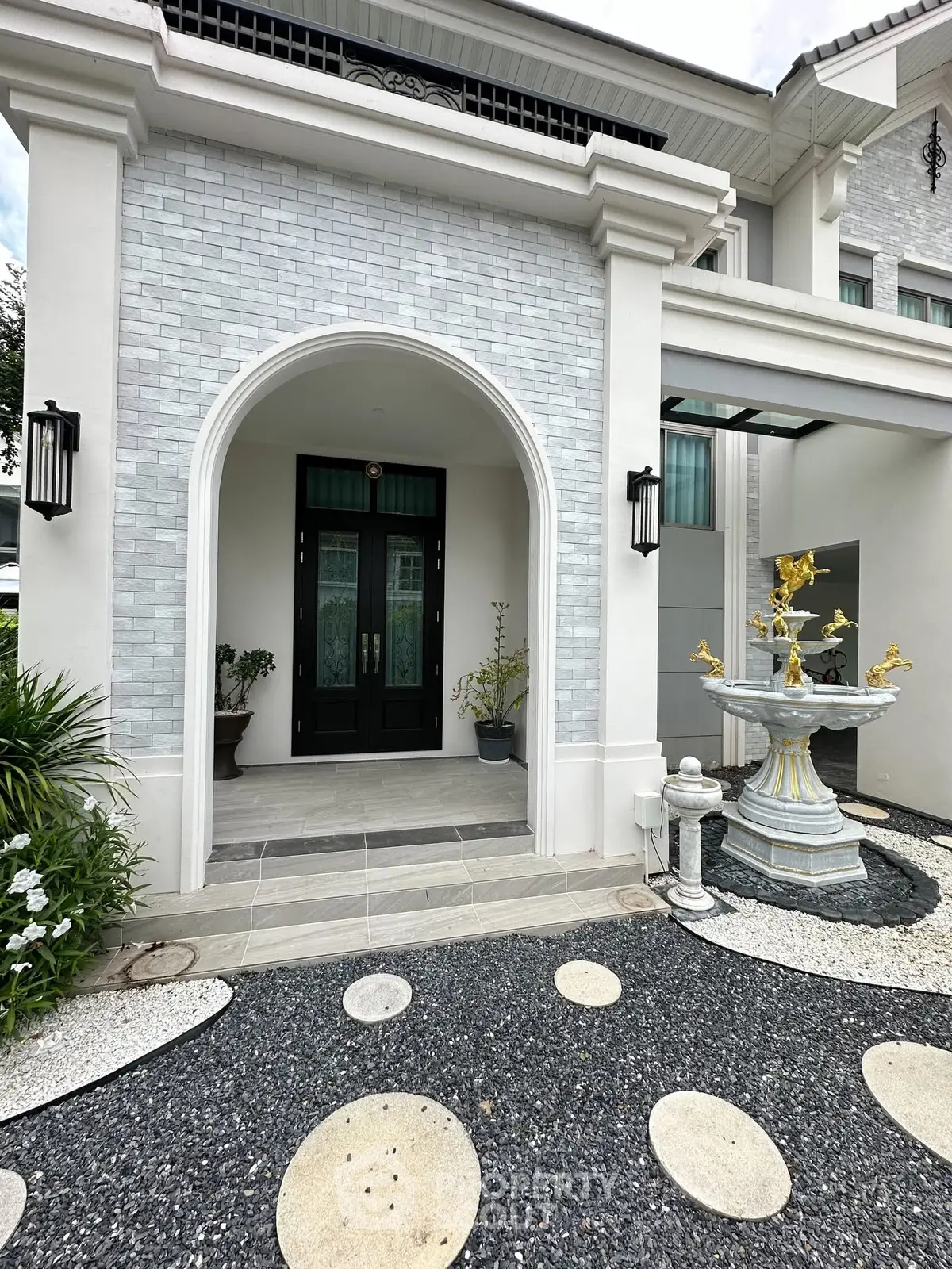Elegant entrance of a luxury home with stylish fountain and modern architecture.