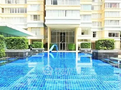 Luxurious apartment building with a stunning blue-tiled swimming pool and lush greenery.