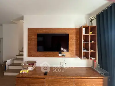 Modern living room with wooden TV panel and shelves, showcasing stylish interior design.