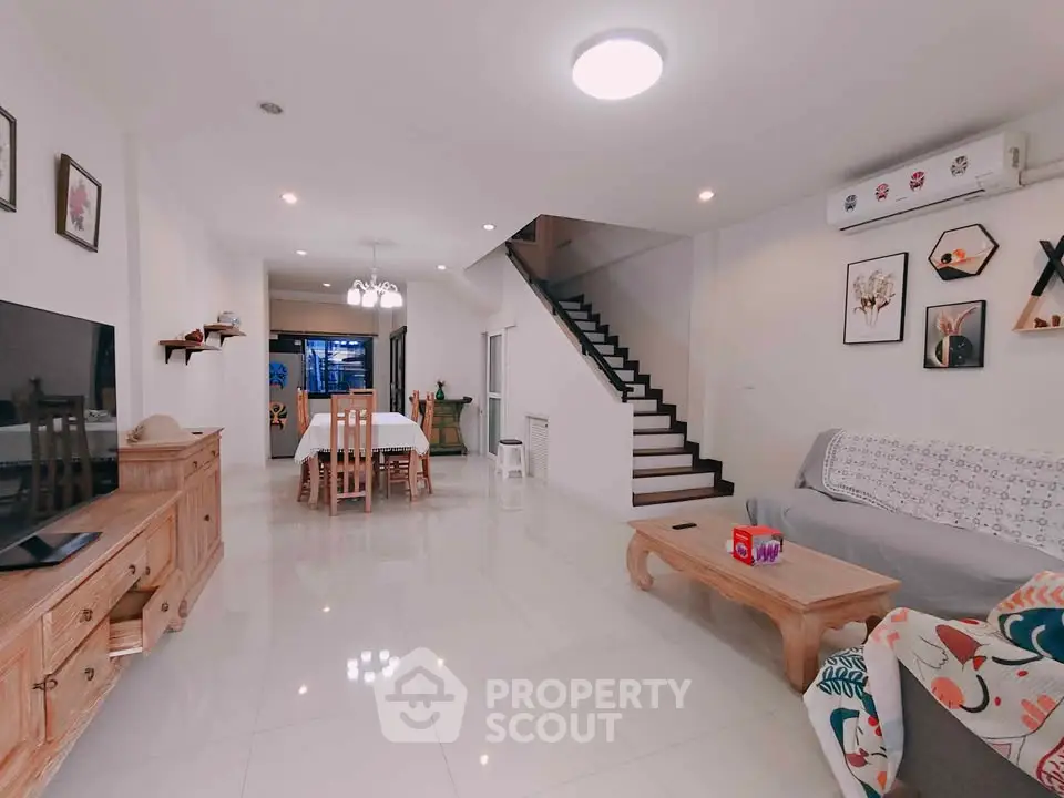 Spacious modern living room with stylish decor and open layout, featuring a cozy dining area and elegant staircase.