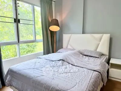 Cozy bedroom with large window and modern decor, perfect for relaxation and comfort.