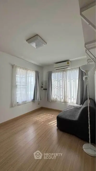 Bright living room with natural light, wooden flooring, and modern air conditioning.
