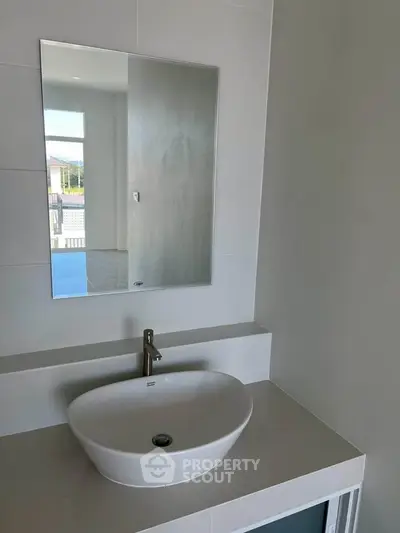Modern bathroom with sleek sink and large mirror, perfect for contemporary living.