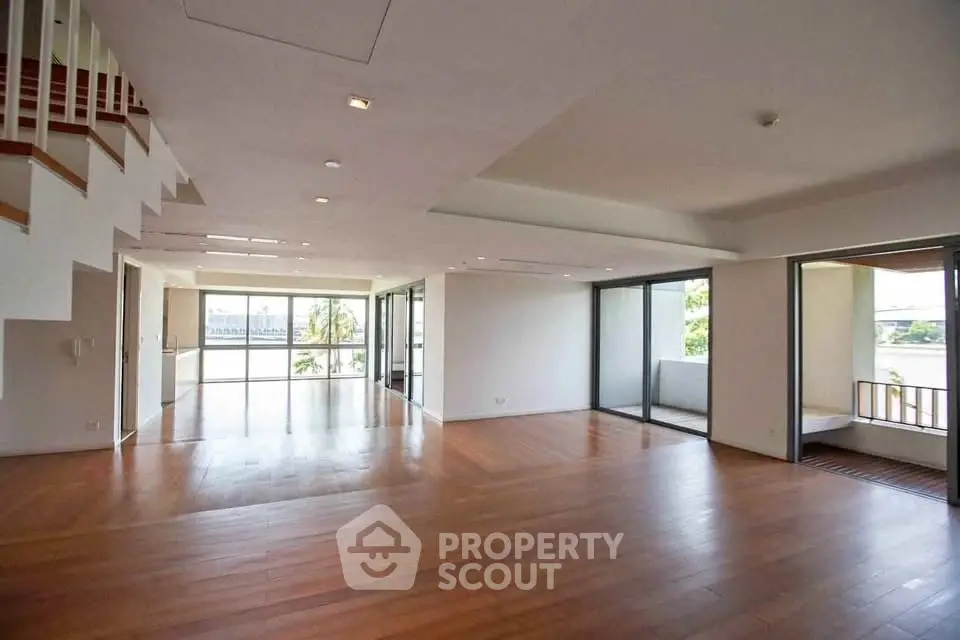 Spacious open-plan living room with hardwood floors and large windows