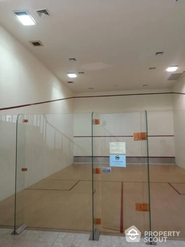 Spacious indoor squash court with glass walls in modern residential complex