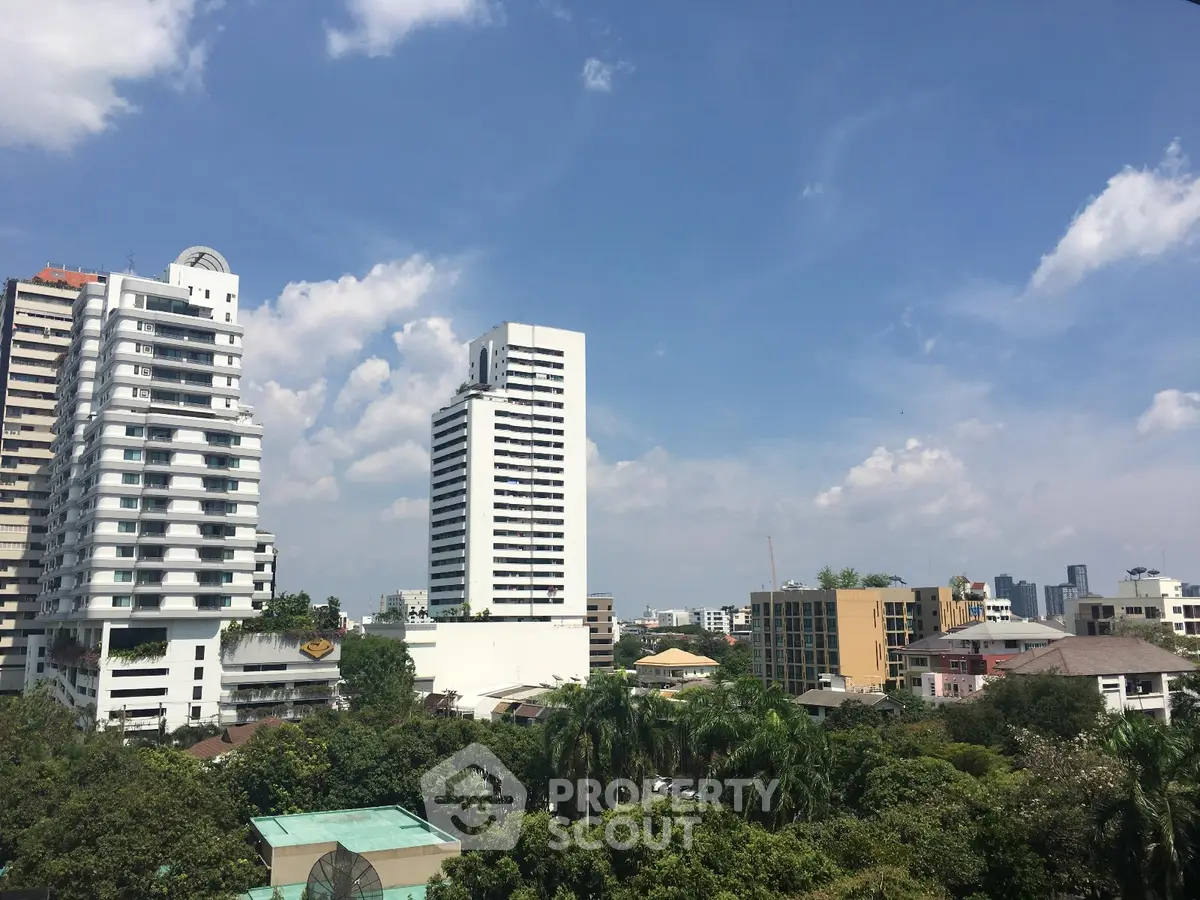 Stunning cityscape view with modern high-rise buildings and lush greenery under a clear blue sky.