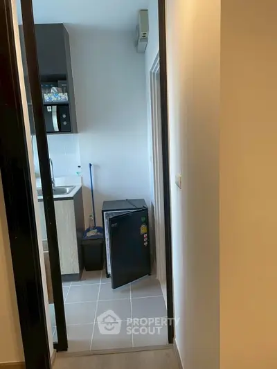 Compact kitchen area with mini fridge and modern cabinetry in cozy apartment.