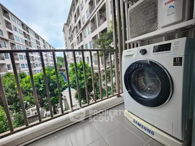 Modern apartment balcony with washing machine and scenic view of residential complex.