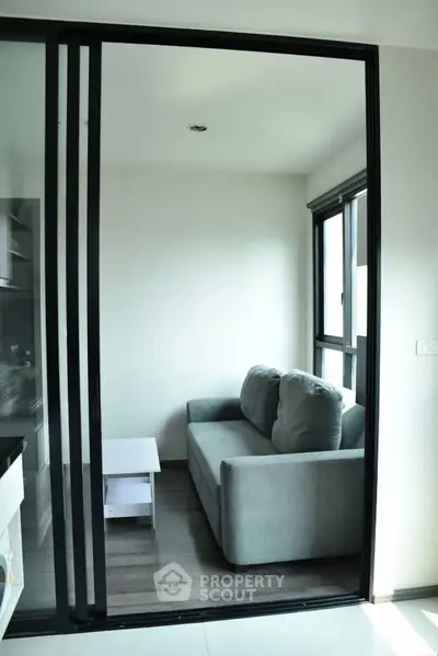Modern living room with sliding glass doors and cozy gray sofa in a bright apartment.